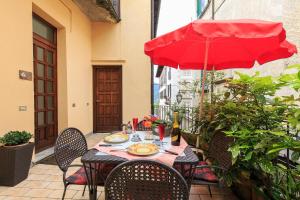 a table with a red umbrella on a patio at Appartamenti Orta in Orta San Giulio