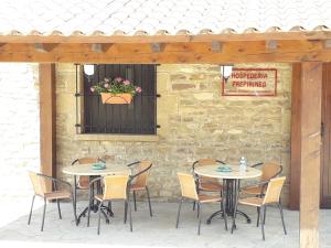 two tables and chairs in front of a stone wall at Hospedería Prepirineo in Undués-Pintano