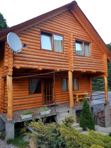 a log house with a porch and a satellite at Guest House Smerichka in Shaian