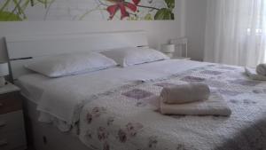 a white bed with two pillows on top of it at Guesthouse Familija Tariba in Supetarska Draga
