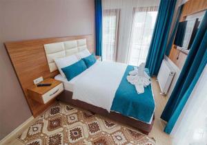 1 dormitorio con 1 cama grande y cortinas azules en Nehir Suite Hotel en Uzungol