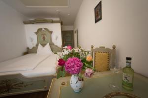 eine Vase mit Blumen auf einem Tisch mit einem Bett in der Unterkunft Hotel Wilder Mann in Passau