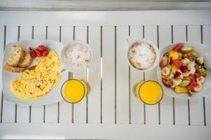a table with two plates of breakfast foods and two cups of coffee at Hotel Mantalena in Antiparos Town