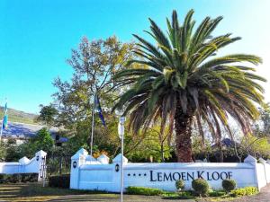 uma palmeira em frente a um edifício com uma placa em Lemoenkloof Boutique Hotel em Paarl