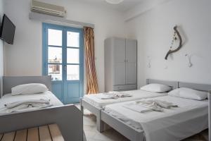 two beds in a room with a window at Hotel Mantalena in Antiparos Town