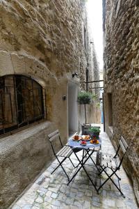 a table and chairs on a patio in an alley at Le petit trésor du Luberon in Ménerbes