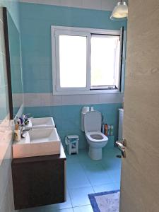 een badkamer met een wastafel, een toilet en een raam bij Irimar retreat managed by Hilltop Residences in Mikra Mandinia