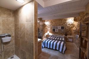 een slaapkamer met een bed in een kamer met stenen muren bij Le petit trésor du Luberon in Ménerbes