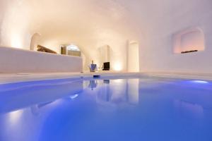 a swimming pool in a white room with blue water at Kampanario Luxury Villa in Megalochori