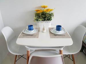 a white table with two cups and a vase with flowers at Cityscape Residences Unit 510 in Bacolod