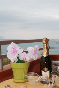 a bottle of wine and a vase with flowers on a table at GB Case Vacanze Sicilia in Balestrate