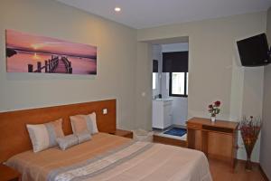 a hotel room with two beds and a television at GuestHouse Belo Horizonte in Porto