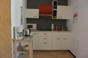 una cocina con armarios blancos y una mesa pequeña. en Auerbachs Keller, en Plauen
