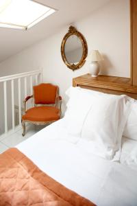 a bedroom with a bed and a chair and a mirror at La Bastide De Moustiers - Hôtel et Restaurant - Teritoria in Moustiers-Sainte-Marie