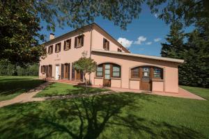 a large pink house with a grass yard at Agriturismo Sant'Uberto in Bolgheri