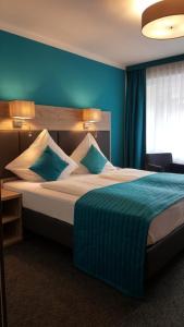 ein Schlafzimmer mit einem großen Bett mit blauen Wänden in der Unterkunft StadtHotel Bad Fallingbostel in Bad Fallingbostel
