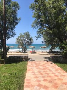 a path to the beach with trees and umbrellas at Rooms Leonidas in Kissamos