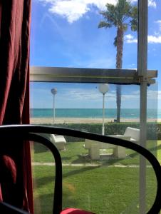 a window with a view of the beach and a palm tree at Playa Esquirol in Cambrils