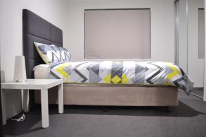 a bedroom with a bed with a yellow and grey comforter at Perth Urban Lodge in Perth