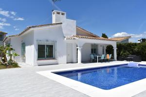 a white house with a swimming pool in front of it at Villa Esmeralda in Estepona