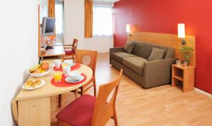 ein Wohnzimmer mit einem Tisch und einem Sofa in der Unterkunft Séjours & Affaires Rennes de Bretagne in Rennes