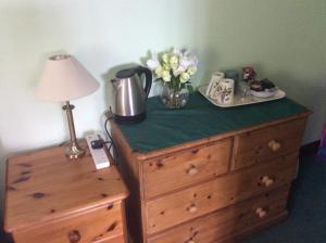 a dresser with a lamp and a table with flowers on it at Poplar Farm in Wedmore