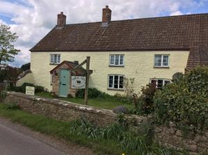 a white house with a green door on a street at Poplar Farm in Wedmore +12 photos