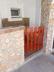 una cerca naranja junto a una pared de piedra en Apartmani Antonella en Premantura