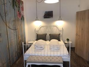a bedroom with a white bed with a bench at Dunakavics Boutique Apartman Szentendre in Szentendre