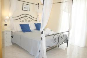 um quarto branco com uma cama com almofadas azuis em City life Pompeii em Pompeia