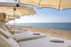 a row of umbrellas and chairs on the beach at Riva Del Sole Resort & SPA in Castiglione della Pescaia