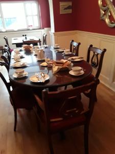 a dining room table with chairs and a wooden floor at Fuchsia House Bed and Breakfast Connemara in Renvyle