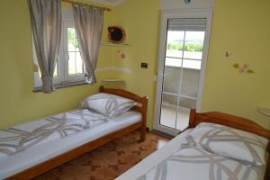 two beds in a small room with a window at Apartman Ika Umag in Umag