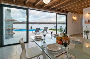 a dining room with a table and a view of a pool at Casa Valeria in Tinajo