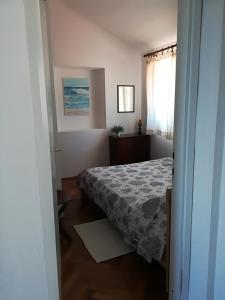 a small bedroom with a bed and a window at Sea-esta 1 in Valun