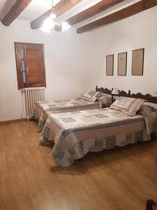 two beds in a white room with wooden floors at Casa Simón in Roda de Isábena