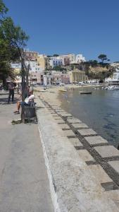 a group of people sitting on a bench next to the water at La Casa Sugli Archi in Ponza