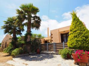 a house with two palm trees and a fence at Traditional Cretan Villa in Rodhopós