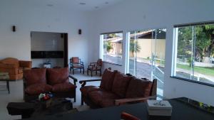 uma sala de estar com sofás, cadeiras e janelas em Hotel Pousada Gurupiá em Serra Negra