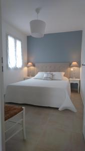 een witte slaapkamer met een groot wit bed met 2 lampen bij LES LAUZES DE ST MICHEL-LA SARRIETTE in Entrechaux