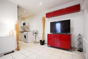 a living room with a red cabinet with a flat screen tv at GregBnb-com - Studio Cosy - CLIMATISÉ - WIFI - 15min Gare in Toulon