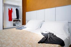 a bedroom with a bed with white sheets and a red dress hanging at Atmosphere Suite Hotel in Rimini