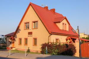 a house with a red roof on a street at Pensjonat Belona in Dziwnów
