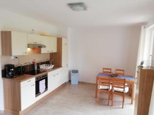 a kitchen with white cabinets and a table and chairs at Fenyves Ferienhaus 1 **** in Balatonfenyves