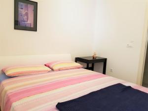 Una cama con una manta a rayas y una mesa negra en Studios Mimoza, en Dubrovnik