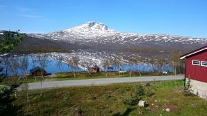 a snow covered mountain with a road and a red barn at Karistua in Hansnes