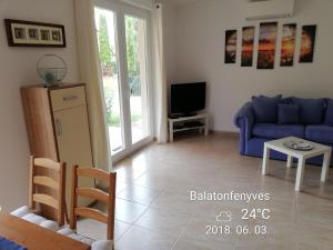 ein Wohnzimmer mit einem blauen Sofa und einem TV in der Unterkunft Fenyves Ferienhaus 1 **** in Balatonfenyves