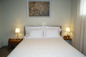 a bedroom with a bed with two lamps and a painting at Melody Apartments in Agios Nikolaos
