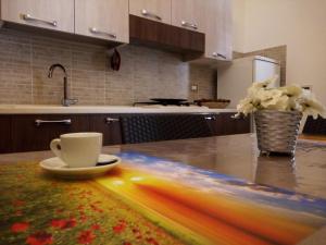 a kitchen counter with a cup and a vase of flowers at Sole in San Vito lo Capo