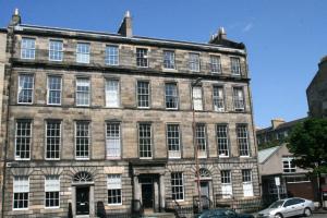 an old stone building with cars parked in front of it at Hopetoun Grande Georgian Apartment in Edinburgh